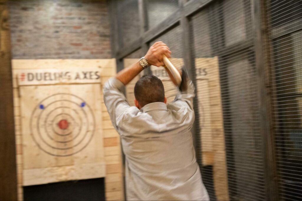 Man throwing a two-handed throw at Dueling Axes' axe throwing lounge